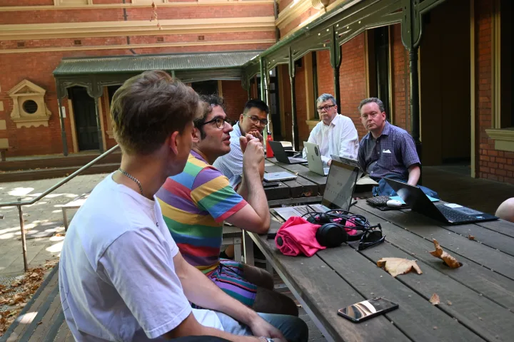 Developers discussing their work around a table with laptops.